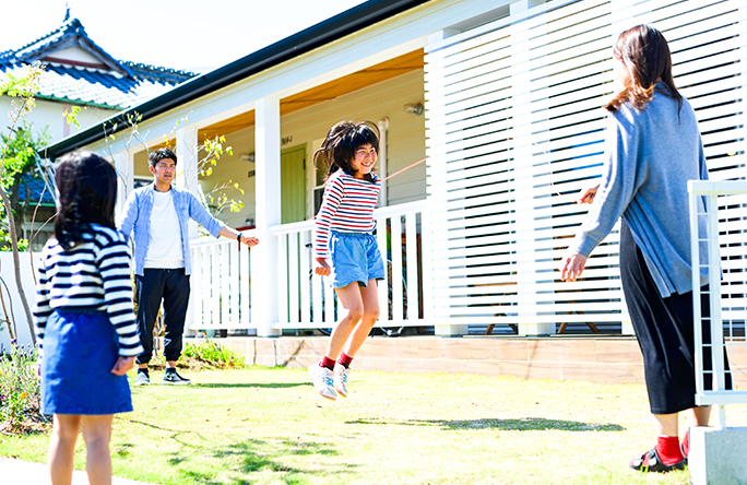 家の庭で子供と縄跳びを楽しむ親子の写真